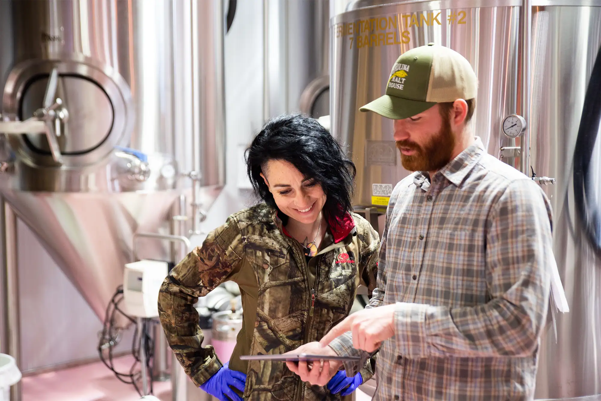 Brewers looking at a clipboard and notes in the brewery production space