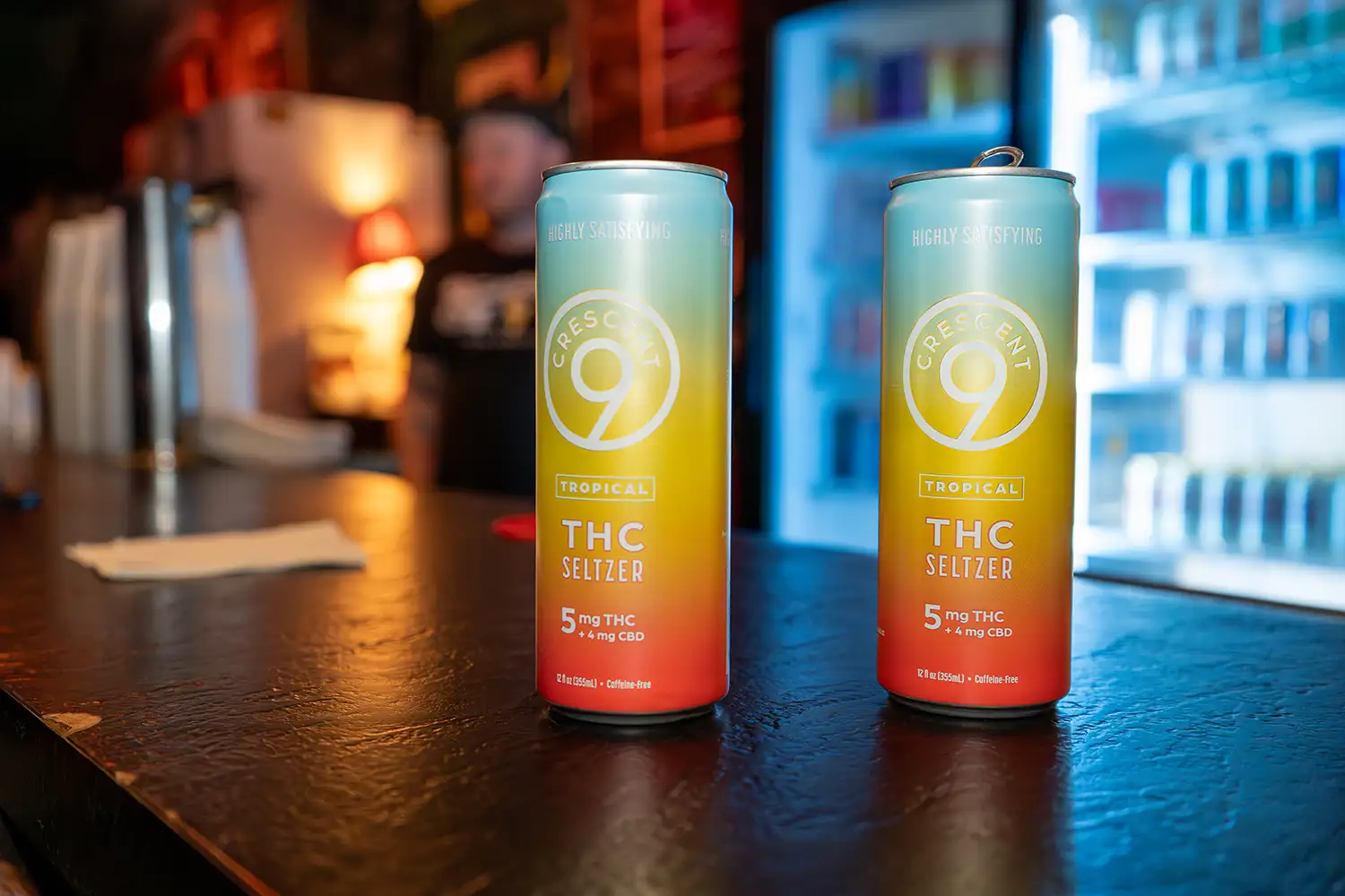 Two cans of Crescent Canna THC beverages on a bar